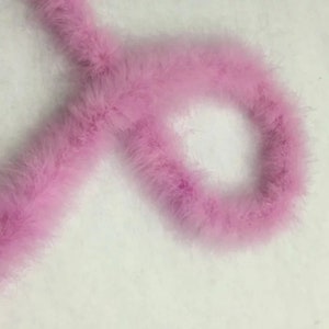 Op de afbeelding: Een lange, roze verenboa. De boa is zacht en pluche, en perfect om een vleugje glamour toe te voegen aan elke outfit.