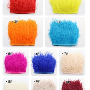 Puede incluir: Diez colores diferentes de ribete de plumas de avestruz, cada color se muestra en un cuadrado separado. Los colores son rojo, amarillo, naranja, azul, rosa, azul oscuro, beige, beige claro y burdeos.