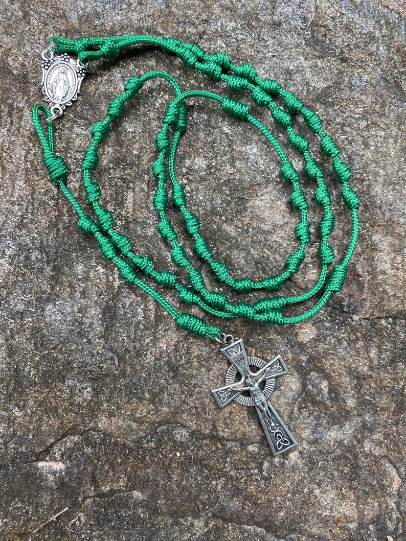 May include: Green knotted rosary with a silver Celtic cross and a silver medal of the Virgin Mary.