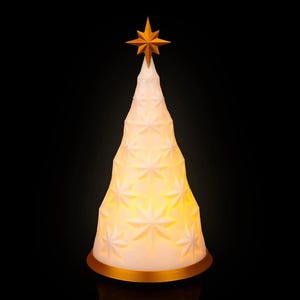 Puede incluir: Un árbol de Navidad blanco con diseño de estrellas, con una estrella dorada en la parte superior y una base dorada. El árbol está iluminado desde dentro, creando un brillo cálido sobre un fondo negro. Una decoración festiva.