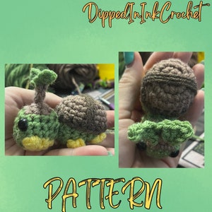 May include: A crocheted green and brown turtle amigurumi toy. The turtle has a yellow belly and black eyes. The toy is being held in a hand. The image includes the text "Dipped In Ink Crochet" and "PATTERN".