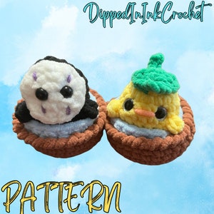 May include: Two crocheted amigurumi toys, a black and white No Face character from Spirited Away and a yellow chick with a green leaf hat, are sitting in brown crocheted baskets. The text "Dipped In Ink Crochet" and "PATTERN" are visible in the image.