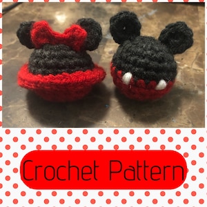 May include: Crocheted Mickey Mouse and Minnie Mouse characters. Mickey is black with white accents and Minnie is black with red accents. The characters are small and have a 3D appearance.
