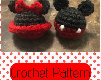 May include: Crocheted Mickey Mouse and Minnie Mouse characters. Mickey is black with white accents and Minnie is black with red accents. The characters are small and have a 3D appearance.