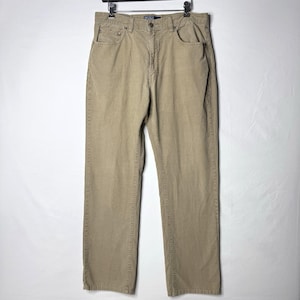 May include: Tan corduroy pants with a classic five-pocket design. The pants are hanging on a black hanger against a white background. The pants have a straight leg cut and a button and zipper closure.