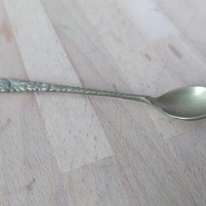 May include: A small, ornate, brass spoon with a textured handle and a rounded bowl.