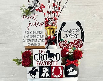 May include: A three-tiered white tiered tray decorated with red roses, black and white polka dots, and signs with the text "mint julep", "run for the roses", "the crowd favorite", "place your bets", "talk derby to me", "derby day kisses", "it's derby time", "and they're off!"