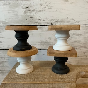 May include: Two tiered cake stands, one with a black base and one with a white base. Both stands have a natural wood top and bottom.
