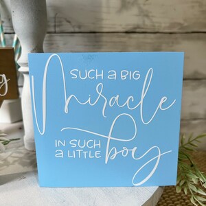K&ouml;nnte beinhalten: Ein hellblaues Holzschild mit wei&szlig;er Aufschrift, die lautet "Such a big miracle in such a little boy".
