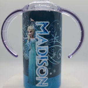 K&ouml;nnte beinhalten: Blau-wei&szlig;er Trinkbecher mit Elsa aus Frozen und dem Namen "Madison". Er hat einen transparenten Deckel, lila Griffe und einen blauen Boden. Geeignet f&uuml;r Kleinkinder.