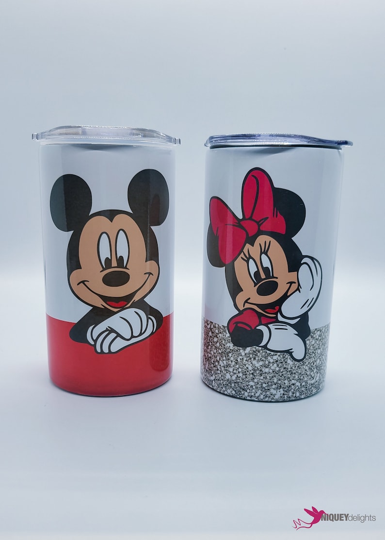 May include: Two stainless steel tumblers featuring Mickey and Minnie Mouse. One tumbler has a red base and Mickey's image, the other has a glitter base and Minnie's image. Both have clear lids.