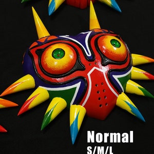 May include: A colorful Majora's Mask replica with yellow, red, green, blue, and black paint. The mask has a sharp, pointed design with spikes around the edges. The text "Normal S/M/L" is visible below the mask.