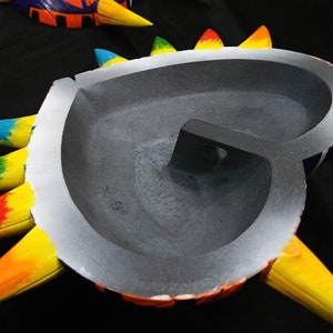 May include: A heart-shaped, colorful, ceramic wall hanging with spikes. The inside of the heart is painted gray.