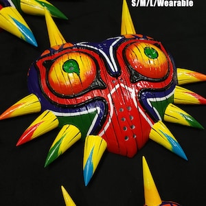 May include: A colorful, wooden Majora's Mask from The Legend of Zelda. The mask is painted with a wood grain pattern and has a red, yellow, green, and blue color scheme. The mask is wearable and comes in sizes S/M/L. Wood Grain S/M/L/Wearable