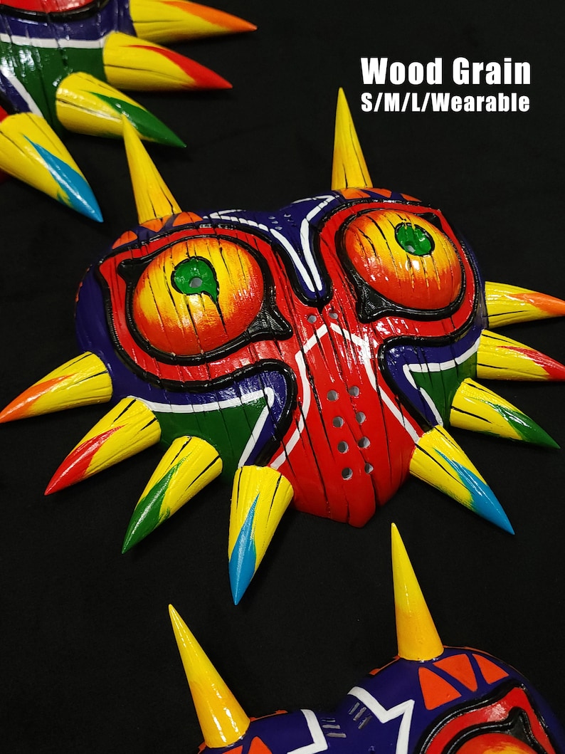 May include: A colorful, wooden Majora's Mask from The Legend of Zelda. The mask is painted with a wood grain pattern and has a red, yellow, green, and blue color scheme. The mask is wearable and comes in sizes S/M/L. Wood Grain S/M/L/Wearable