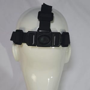 May include: Black headlamp strap with adjustable buckles and a top strap, designed to fit around the head. The strap is shown on a white mannequin head, against a white background. The strap is made of a durable, woven material.
