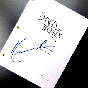 May include: A white script for "Dances With Wolves" with the title in elegant script. The script is signed in blue ink. The text "Dances With Wolves by Michael Blake" is visible. The date "May 23, 1989 Final Draft" is also present.