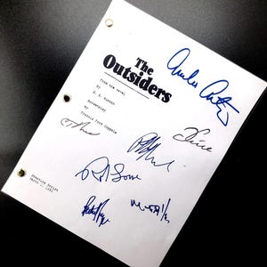 May include: A white script page from the movie "The Outsiders" with the title and credits. The page is signed by several people, including Francis Ford Coppola, the screenwriter, and the actors Ralph Macchio, Matt Dillon, and C. Thomas Howell.