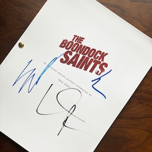 以下が含まれることがあります： 「The Boondock Saints」と題された白い脚本。タイトルは赤色で、「SAINTS」の文字は風化したフォントで書かれています。 脚本は青と黒のインクで署名され、2つの真鍮製の留め具で固定されています。