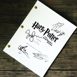 Op de afbeelding: Een witte scriptpagina voor de film "Harry Potter en de Steen der Wijzen" met handtekeningen van de cast en crew. De handtekeningen omvatten "Chris Columbus", "Steve Kloves" en "J.K. Rowling".