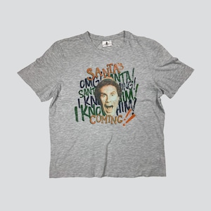 May include: A gray t-shirt with a graphic print of a man's face with the text "SANTA'S" and "COMING!" in green and orange.