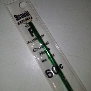 May include: Green aluminum crochet hook size P, labeled "Scovill HERO" and "60c".