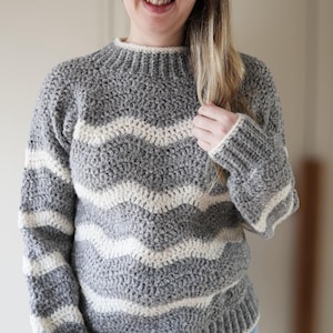 May include: A gray and white striped crocheted sweater with a mock neck.