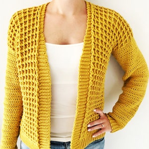 May include: A yellow crocheted cardigan with a waffle stitch pattern. The cardigan has a V-neck and long sleeves.