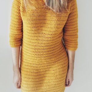 May include: A mustard yellow crocheted hooded dress with long sleeves.