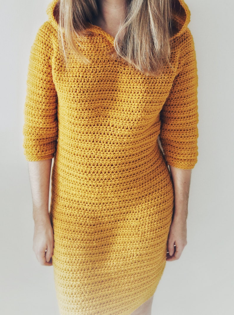 May include: A mustard yellow crocheted hooded dress with long sleeves.