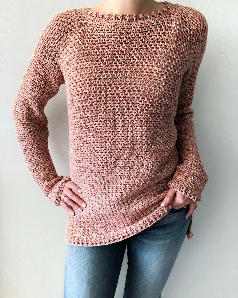 May include: A long-sleeved, pink and white crocheted sweater with a loose fit.