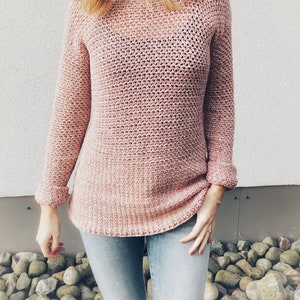 May include: A pink crocheted sweater with a loose fit and long sleeves. The sweater has a subtle ombre effect, transitioning from a lighter pink to a darker pink.