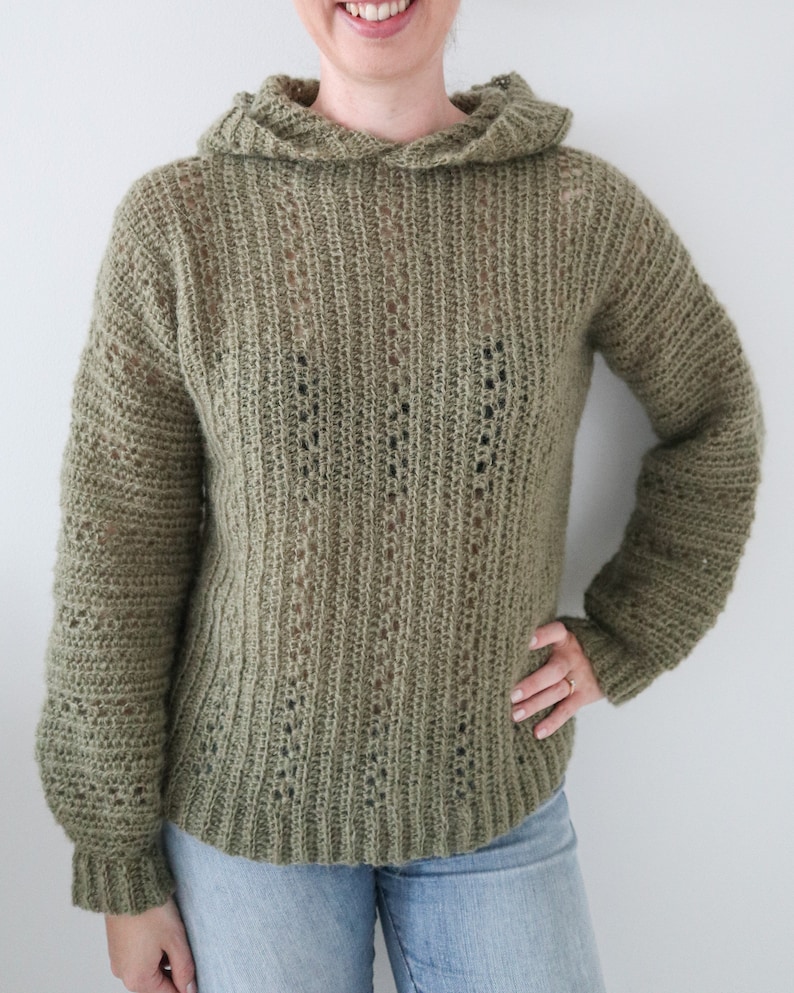 May include: A green crocheted hooded sweater with a loose fit and long sleeves.
