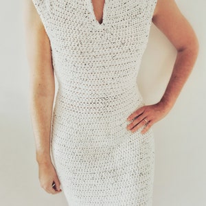 May include: A white crochet dress with a v-neck and sleeveless design.