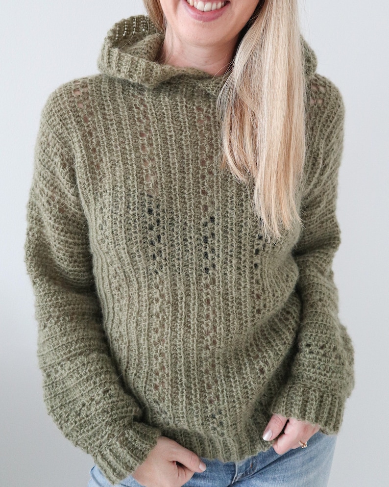 May include: A green knitted hooded sweater with a loose fit and a textured pattern.