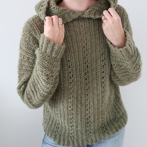 May include: A green crocheted hooded sweater with a loose fit and a ribbed texture.