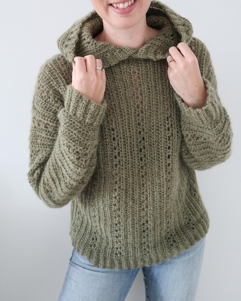May include: A green crocheted hooded sweater with a loose fit and a ribbed texture.