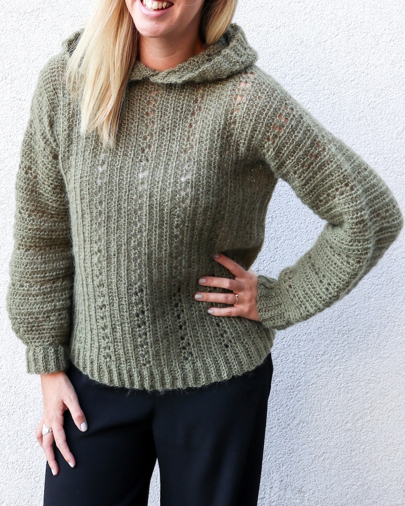 May include: A green crocheted hooded sweater with a loose fit and a delicate stitch pattern.