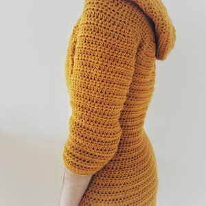 May include: A mustard yellow crocheted hooded dress with long sleeves.