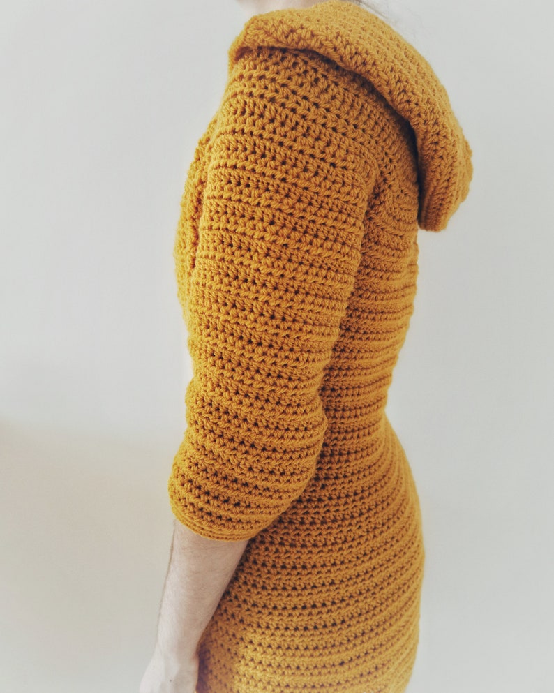May include: A mustard yellow crocheted hooded dress with long sleeves.