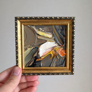 Pintura al óleo abstracta texturizada de 4 x 4 pulgadas, trazos terrosos audaces, tonos cálidos de naranja, gris oscuro y blanco suave en un marco dorado y negro, decoración de pared ecléctica