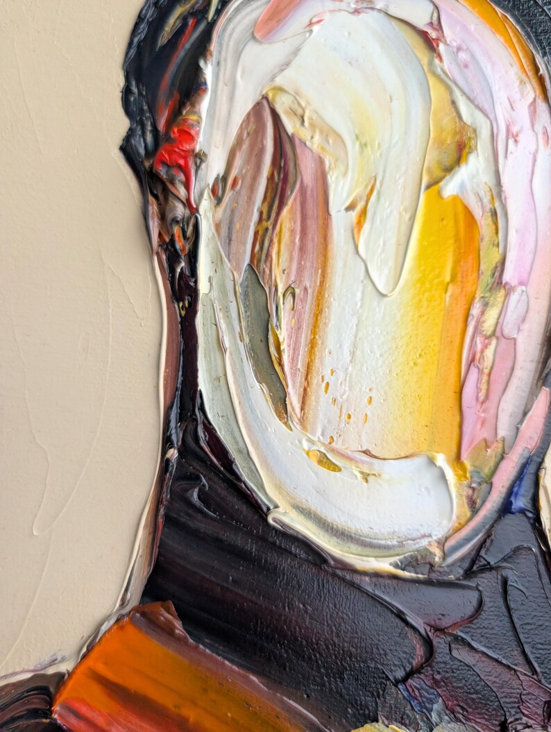 Puede incluir: Primer plano de una pintura al &oacute;leo abstracta que presenta un retrato con gruesas pinceladas. La obra de arte utiliza una paleta de blanco, amarillo, naranja, marr&oacute;n y negro, creando un efecto texturizado y expresivo. El fondo es beige neutro.