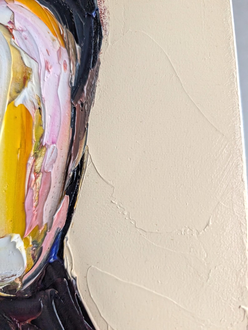 Puede incluir: Primer plano de una pintura al &oacute;leo abstracta que presenta un retrato con gruesas pinceladas. La obra de arte utiliza una paleta de amarillo, rosa, negro y blanco, con un fondo beige neutro. La pintura texturizada crea un efecto tridimensional.