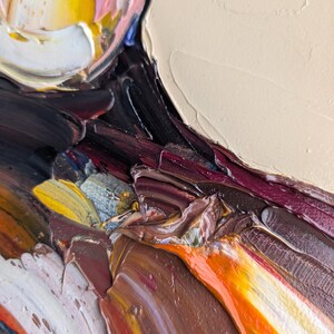 Puede incluir: Primer plano de una pintura al &oacute;leo abstracta con gruesas pinceladas. La obra presenta una paleta de colores que incluye amarillo, blanco, rosa, marr&oacute;n, naranja y negro. La textura es muy visible, creando un efecto tridimensional.
