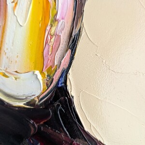 Puede incluir: Primer plano de una pintura al &oacute;leo abstracta con gruesas pinceladas. La obra presenta una paleta de colores que incluye amarillo, rosa, blanco, negro y burdeos. La textura es muy empastada, creando un efecto tridimensional.