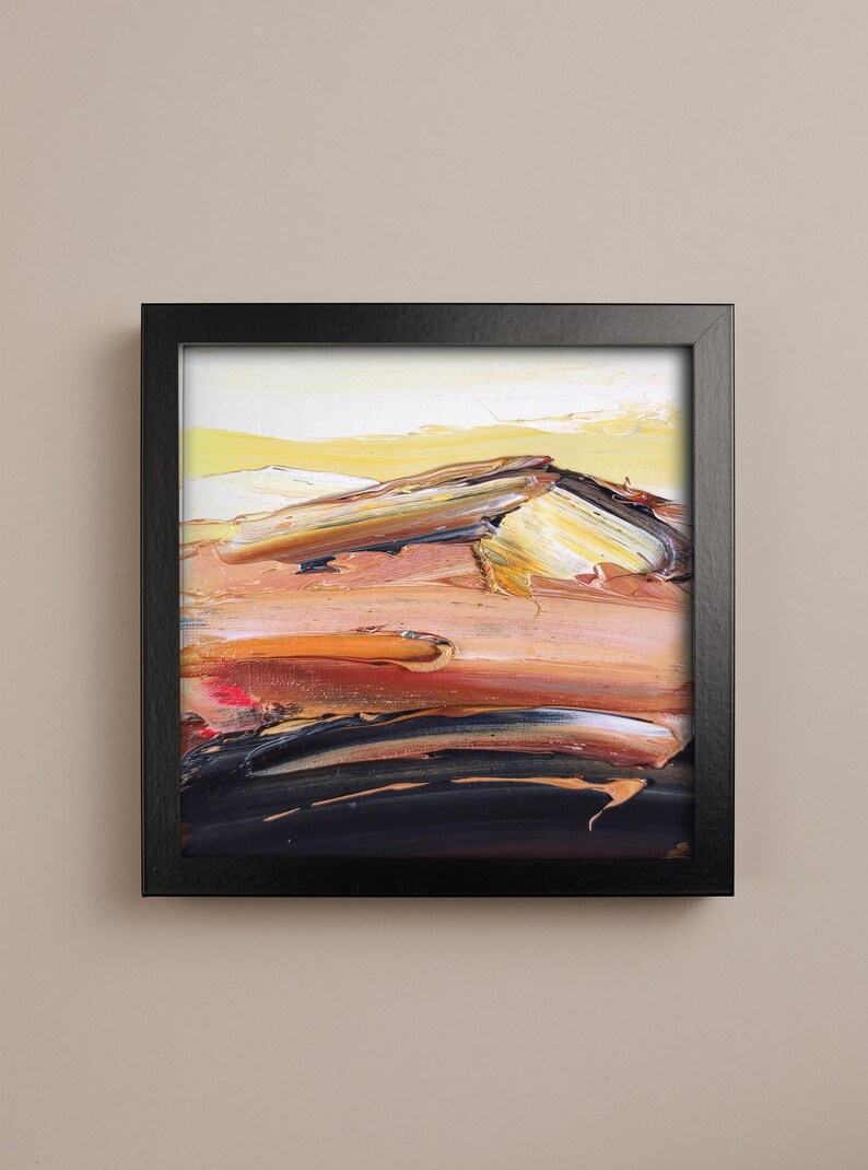 May include: Abstract oil painting in a black frame. The artwork features textured brushstrokes in shades of yellow, orange, brown, and black, creating a landscape-like composition. The painting evokes a sense of warmth and depth.
