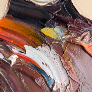 Puede incluir: Primer plano de una pintura al &oacute;leo abstracta con pinceladas gruesas. La obra presenta una paleta de colores que incluye marr&oacute;n, blanco, naranja, amarillo y negro. La textura est&aacute; muy estratificada, creando un efecto tridimensional.
