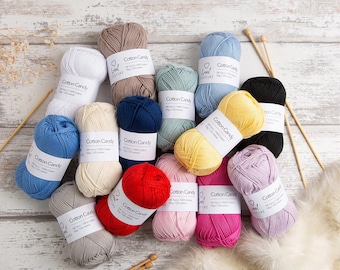 May include: Assortment of 14 skeins of Cotton Candy yarn in various colors, including white, beige, light blue, navy blue, light green, yellow, pink, red, and grey. Each skein has a label that reads "Cotton Candy" and "Love Couture".