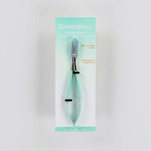 May include: A pair of blue sharp snips with a micro-serrated blade. The snips are lightweight and ergonomic. The packaging is light blue with the brand name "Kimberbell" printed on it.