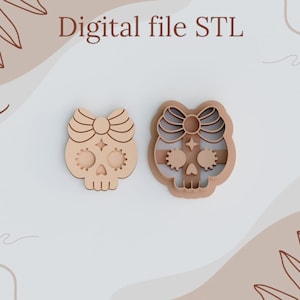 May include: Two wooden cookie cutters shaped like a skull with a bow on top. The skull has a star and eye details. The cookie cutters are on a white background with brown swirls.